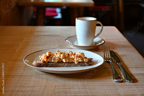delicious traditional rustic Bavarian cheese called Obazda on the piece of the rustic bread wooden table at an alpine cafe in the Bavarian Alps