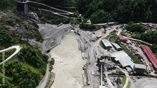 Cinematic aerial footage of a remote construction site in the Himalayas showing the layout of the base camp roads and the river diversion for a clean energy major project.