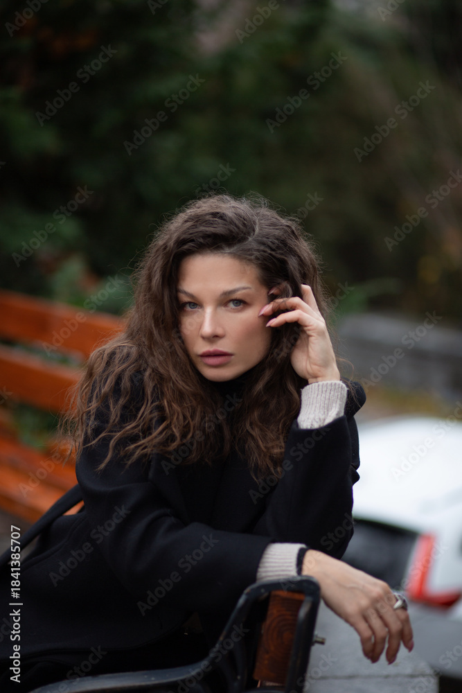 Fototapeta premium Woman sitting outdoors with curly hair