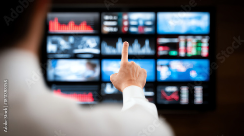 Business professional analyzing data trends on multiple screens, focusing on statistics and financial performance metrics.