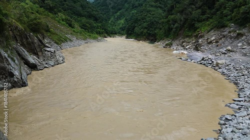 Drone view of water infrastructure in a remote area showing a hydropower dam intake gate on a sediment rich river in the mountainous terrain of Nepal for clean electricity