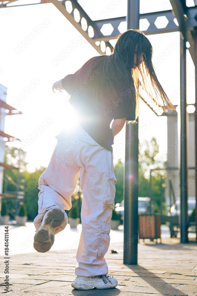 Fototapeta premium Young dancer showcases talent outdoors during sunset in urban park setting