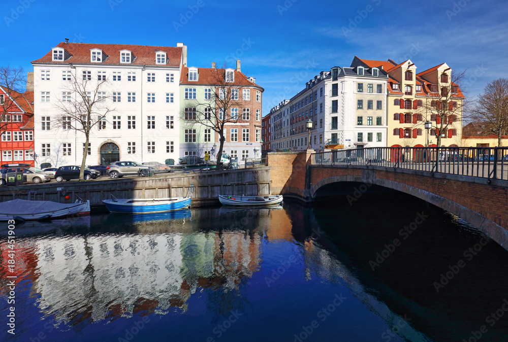 Naklejka premium Copenhagen christianshavn canal with boats in old town. Famous tourist spot in Denmark with colorful historical buildings. Nyhavn Harbor