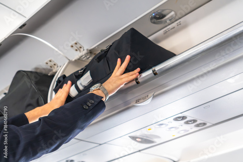 Businessman placing luggage in overhead compartment on airplane