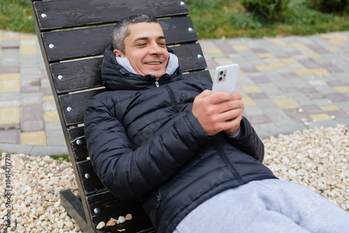 Photos A man lies back on a lounge chair, enjoying a sunny day in the park