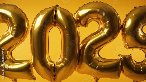 Golden balloons forming the number 2025 against yellow background