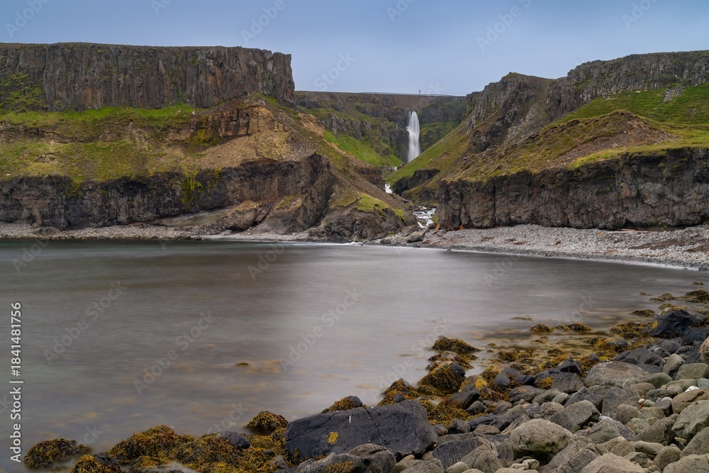 Fototapeta premium view of the Iceland coast and cliffs near Vopnafjordur with the Gljufursarfoss waterfall in the distance