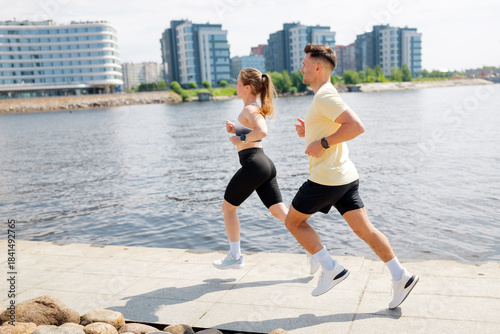 Couple jogging along river in urban setting