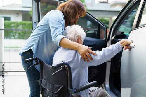 Caregiver help Asian elderly woman disability patient use wheelchair to get in car.