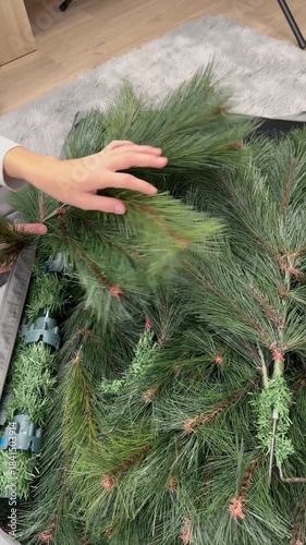 Person carefully placing a disassembled artificial christmas tree into a grey storage bag after the holidays, packing it away for the off-season until the next year's celebration