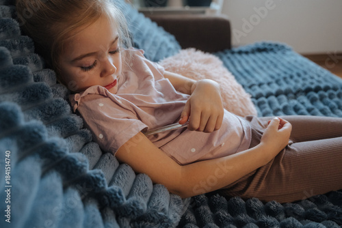 Girl sits on couch while holding a spoon in her hand during the afternoon