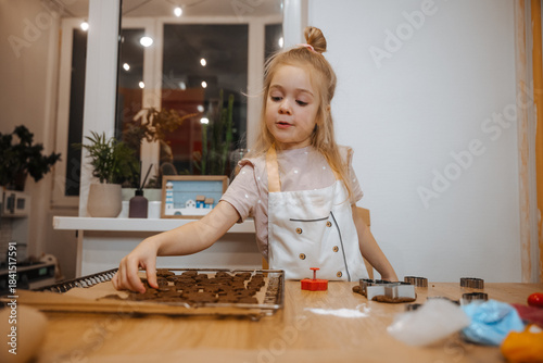 Girl making cookies with dough on a wooden table in a bright kitchen