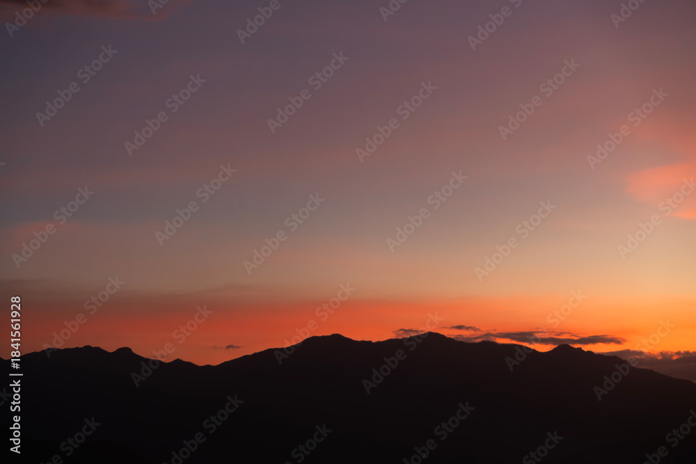 Fototapeta premium Bright sunset over the silhouette mountains at evening time.
