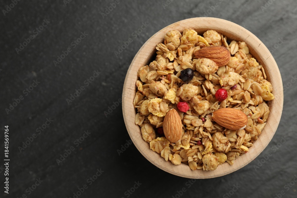 Fototapeta premium Tasty granola with dried fruits and nuts in bowl on black table, top view. Space for text