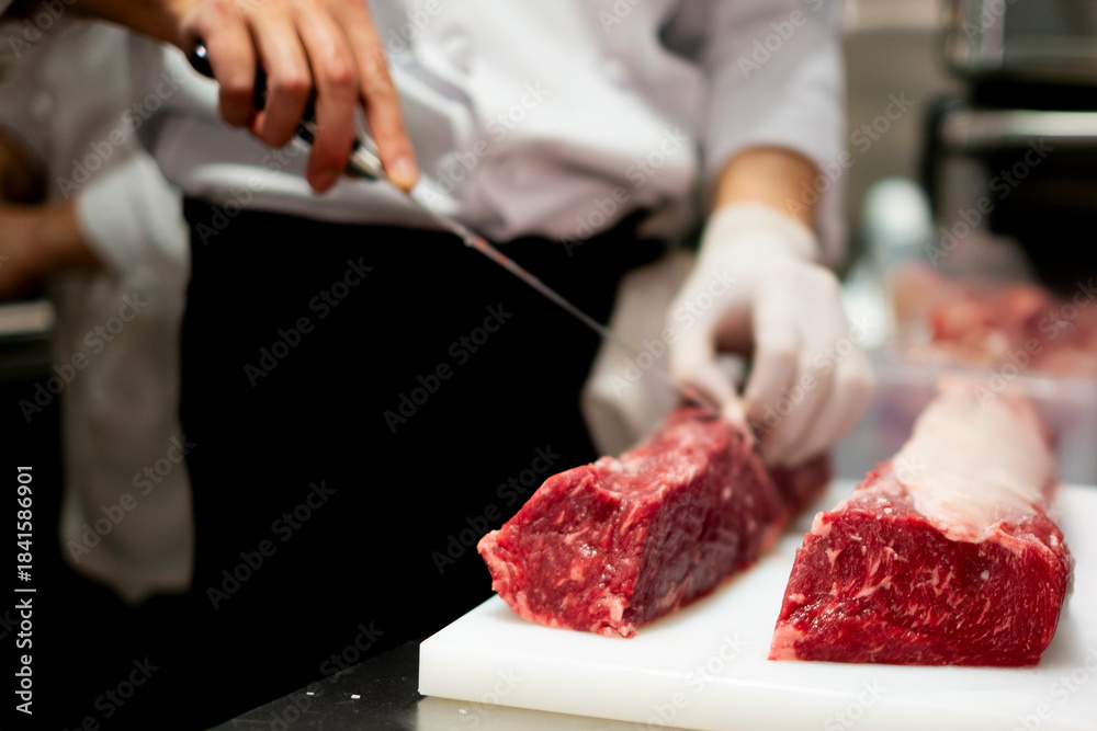 Obraz premium 肉の塊を切るシェフ