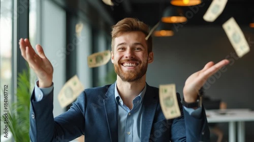 Cheerful young businessman in a modern office tosses US dollar bills in the air, celebrating financial success, bonus or investment profit. Concept of wealth, cash flow and achievement.