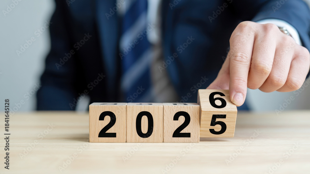Naklejka premium Businessman changing year to 2026 on wooden blocks