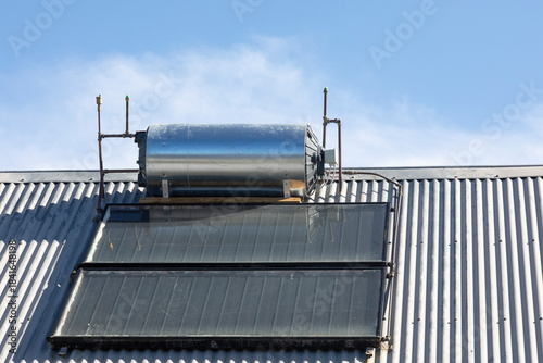 Rooftop solar hot water cylinder with photovoltaic cells  on rural house converting renewable sustainable energy of the sun for electricity and heating