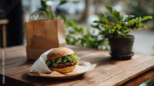 Plant based burger on wooden table with greenery, showcasing eco friendly dining