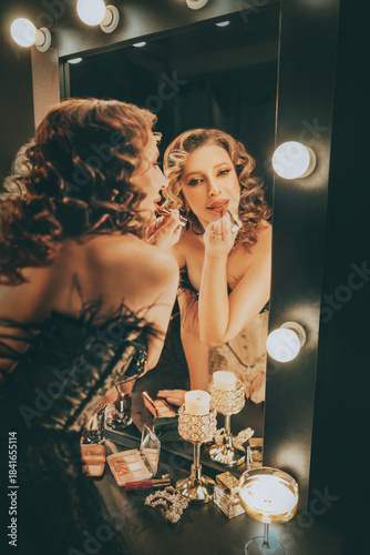 real person blonde hair retro lady looking into mirror painting lips with lipstick, gloss cosmetics. sexy woman burlesque show actress, preparing makeup. Flapper girl 20s roaring twenties old style