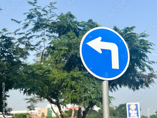 Fotografie A clear, bright image of a circular blue mandatory road sign indicating a turn left ahead