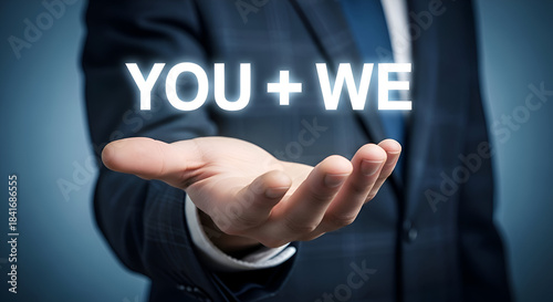 Businessman in blue suit holding hand with you we text floating above palm, partnership and teamwork concept with professional man in formal wear on blue background