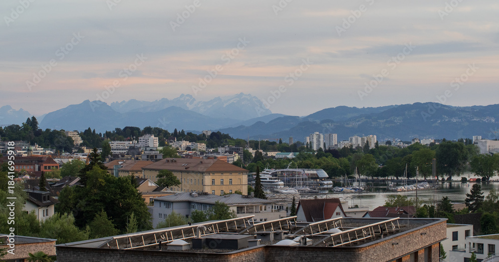 Fototapeta premium Bregenz city skyline with Lake Constance marina and alpine mountain backdrop at dusk