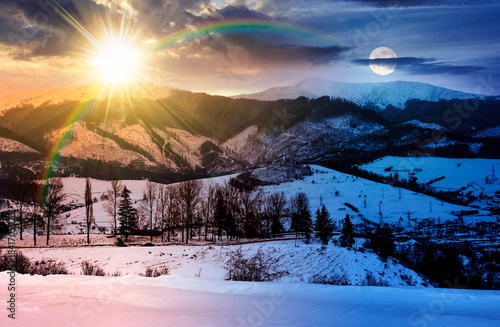 winter solstice sky over the mountains. day and night time change concept. beautiful light on snowy tops of ridge with sun and moon. serpentine pass in to valley. duality and transition template