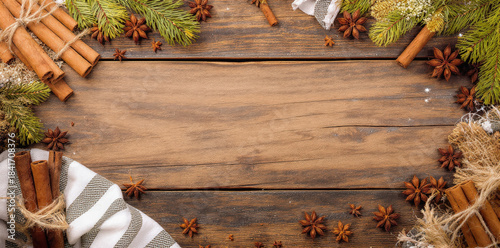 Rustic wooden table with fir branches, cinnamon, star anise, festive cozy holiday background