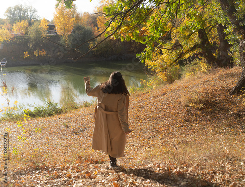 Quadro su tela A person is walking by a lake with trees in bright autumn colors in the afternoo