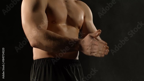 A bodybuilder poses against a black background