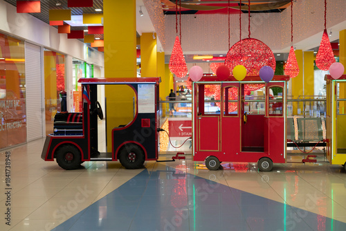 Children enjoy a ride on a small train inside a colorful indoor play area