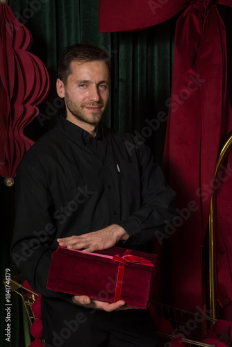 A young handsome man in a black shirt holds a gift in his hands