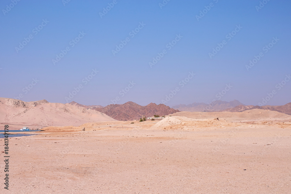 Fototapeta premium Expansive desert landscape with distant mountains under clear blue sky