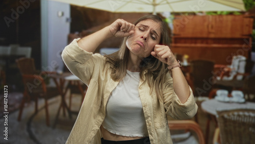 Εκτύπωση καμβά Woman pulls cheeks downward and clenches fists in building while pouting expression; sadness frustration