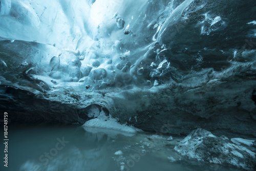 View of ethereal blue ice cave formations reflecting in a crystalline pool of water, creating a surreal and otherworldly scene, Vatnajokull, Southern Iceland, Iceland.