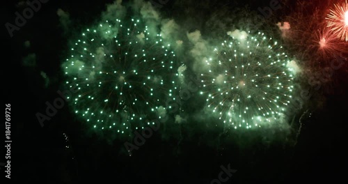 A vibrant golden fireworks display illuminating the night sky over a calm water surface, reflecting bursts of golden light, Christmas or New year celebration or countdown