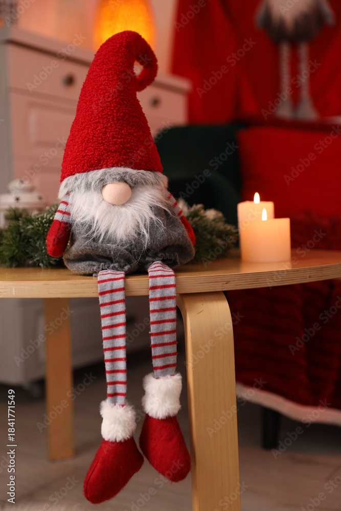 Obraz premium Cute Christmas gnome, burning candles and wreath on wooden table indoors