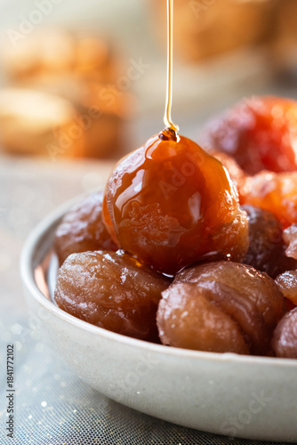Close up of French tradition candied chestnut or marron glacé,  while syrup pouring on it. It's a confection consists of a chestnut candied in sugar syrup and glazed.