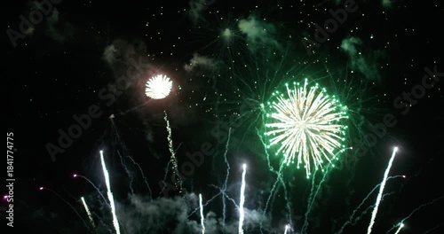 A vibrant golden fireworks display illuminating the night sky over a calm water surface, reflecting bursts of golden light, Christmas or New year celebration or countdown