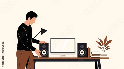 Man setting up speakers at a home studio workspace with a computer and desk