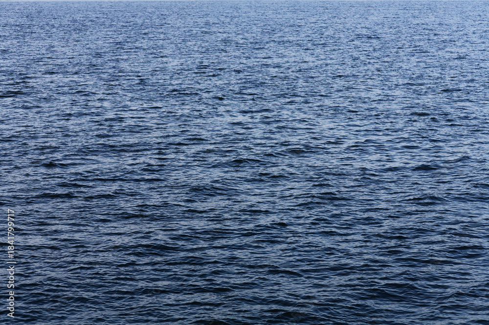 Fototapeta premium Serene Ocean Waves: Sunlit Water Ripples on Calm Blue Sea, Horizontal Close-Up Shot