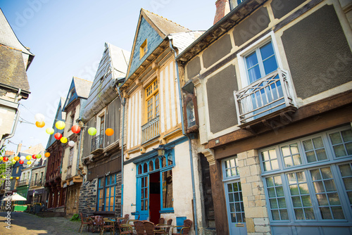 Fototapeta Naklejka Na Ścianę i Meble -  Rue d'en Bas, one of the medieval streets in old town center of Vitré, Brittany, France, with half timbered houses and colorful lantern garlands..