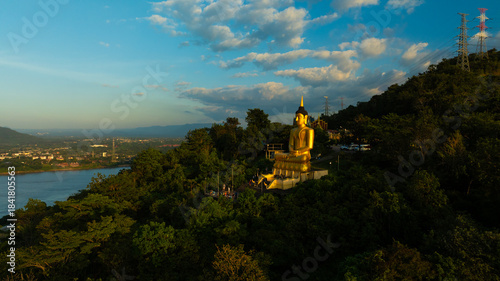 Aerial view at sunset above the Mekong river in Laos revealing Pakse city golden giant buddha