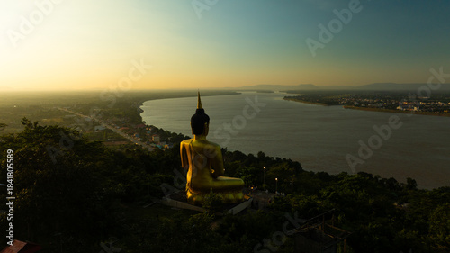 Aerial view at sunset above the Mekong river in Laos revealing Pakse city golden giant buddha