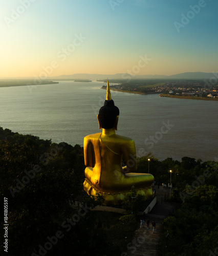 Aerial view at sunset above the Mekong river in Laos revealing Pakse city golden giant buddha