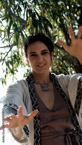 A beautiful brunette dressed in boho style meditates and dances in the forest. A magical ritual takes place against a green forest backdrop.