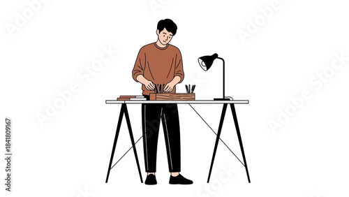 A man is standing at a desk holding pencils and working on creative projects