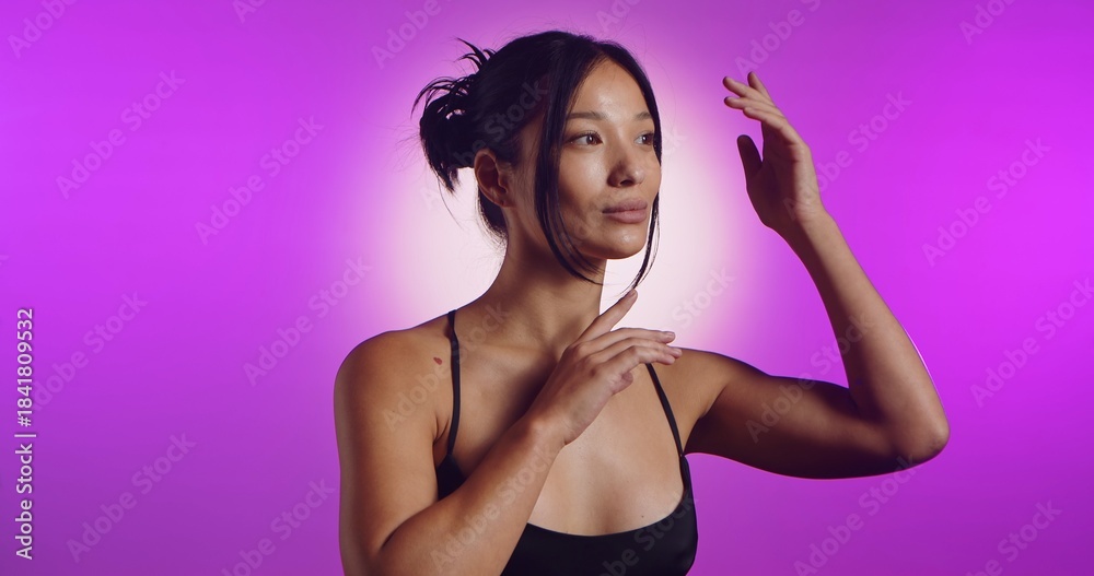Obraz premium A young Korean model poses in a studio lit by pink neon lights