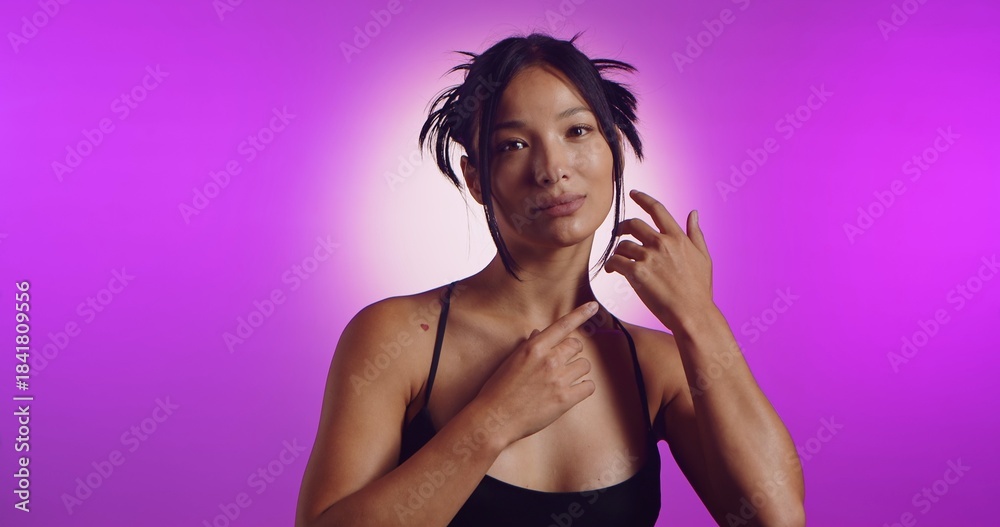 Obraz premium A young Korean model poses in a studio lit by pink neon lights